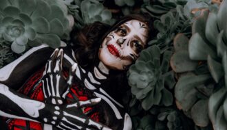 a woman in a skeleton costume lying between plants