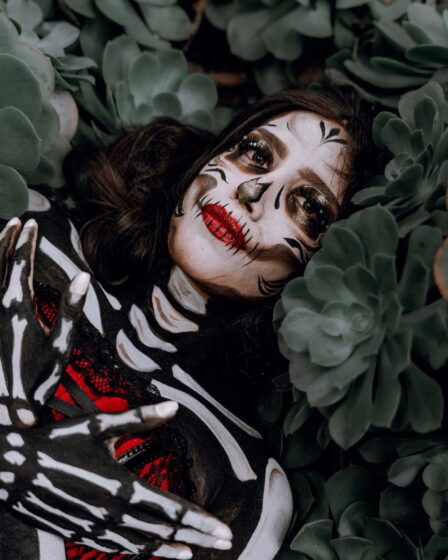 a woman in a skeleton costume lying between plants