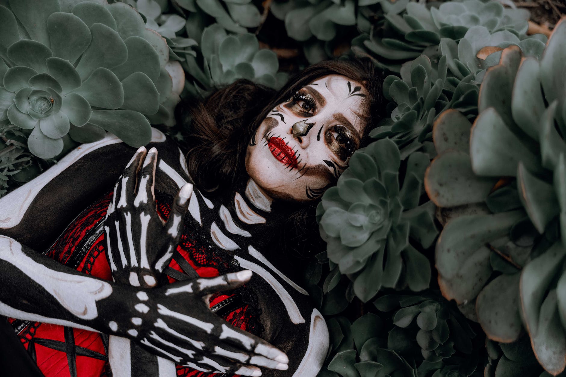 a woman in a skeleton costume lying between plants